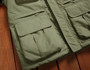 Detail of army green outdoor jacket featuring multiple functional pockets and durable fabric
