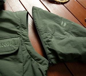 Detail of the detachable sleeve zipper and classic shield embroidery on green jacket