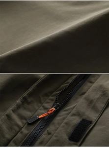 Detail of waterproof olive jacket fabric with black zipper and orange pull cord