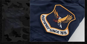 Detail of embroidered eagle shield patch and silk-like fabric on navy bomber jacket