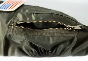 Macro detail of military flight jacket sleeve featuring nylon fabric and a utility pocket