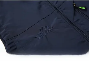 Detail of navy outdoor vest showing mountain embroidery and zipper with green puller