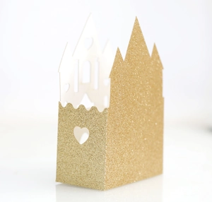 Detail of gold glitter castle favor box with intricate heart-shaped hollow cutouts