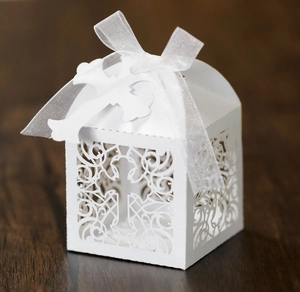 Detailed macro view of laser-cut white cross favor box with decorative white organza ribbon