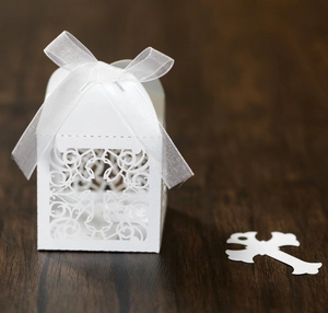 Detail of white laser-cut hollow candy box with cross pattern and silk ribbon