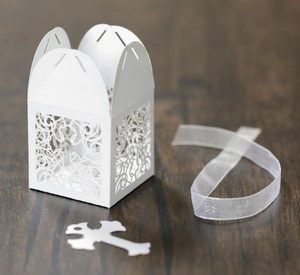 Detailed view of white laser-cut hollow cross wedding gift box with ribbon on wood