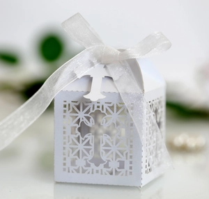 Detail of white laser-cut hollow candy box with cross pattern and white organza ribbon