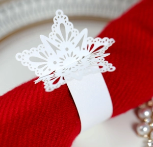 Detail of white laser-cut snowflake napkin ring on red knitted fabric for Christmas decor