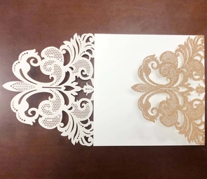 Detail of laser-cut European wedding invitations with silver glitter floral patterns