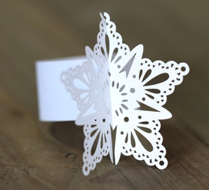 Detail of white laser-cut snowflake napkin ring on a vintage brown wooden surface