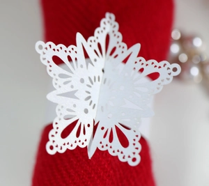 Detailed close-up of white laser-cut snowflake napkin ring on festive red fabric