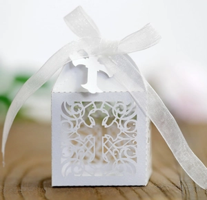 Macro detail of laser-cut pearl white candy box with cross pattern and organza ribbon