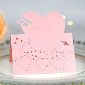 Laser-cut pink heart place card with pearlescent finish on a gold-rimmed plate