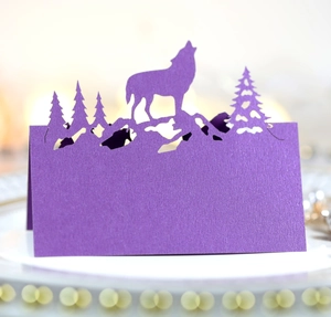 Détail macro d'un marque-place violet découpé au laser avec loup hurlant sur montagne