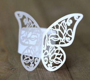 Detailed macro view of laser-cut white paper butterfly napkin ring with floral patterns