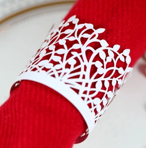 Detailed laser-cut white leaf napkin ring on red fabric for wedding table decor