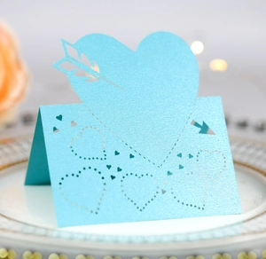 Macro shot of light blue laser-cut heart seat card with pearlescent finish on white plate