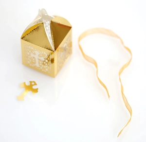 Detail of laser cut gold favor box with hollow cross patterns and matching ribbon