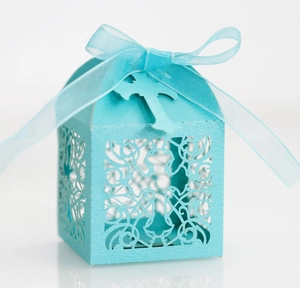 Detail of light blue laser-cut cross favor box with matching organza ribbon and card