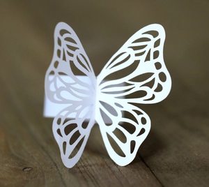 Detailed laser-cut white paper butterfly napkin ring with intricate hollow floral patterns
