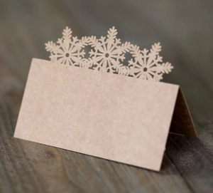 Close-up of laser-cut snowflake hollow details on kraft paper wedding place cards