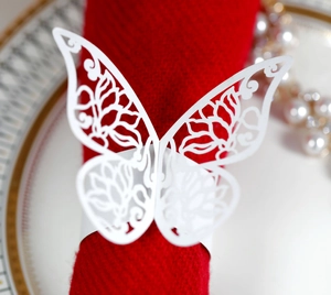 Macro shot of white laser-cut butterfly napkin ring on a deep red napkin for wedding