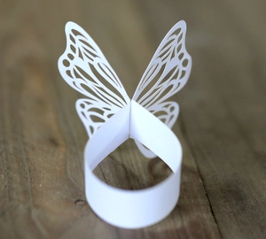 Macro shot of white laser-cut butterfly paper napkin ring on dark wood surface