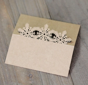 Detail of laser-cut snowflake hollow on kraft paper table place cards for weddings