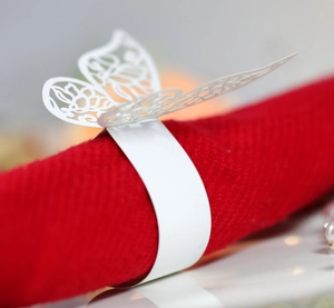 Close-up of white butterfly napkin ring with laser-cut hollow patterns on red fabric