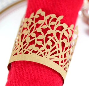 Macro detail of gold laser-cut leaf napkin ring on a red cloth for wedding decor