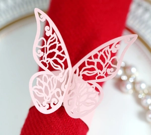 Detailed macro of pink laser-cut butterfly napkin ring on a red wedding serviette