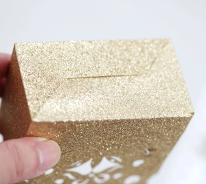 Close-up of champagne gold glitter candy box with intricate laser-cut hollow patterns