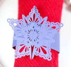 Close-up of laser-cut purple snowflake napkin ring on a festive red napkin