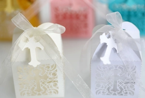 Detail of laser-cut cross pattern on white pearl paper candy boxes with white ribbons