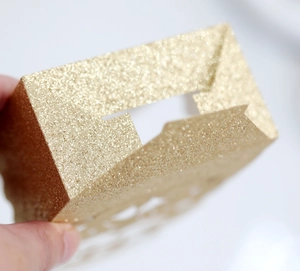 Close-up of golden glitter gift box with laser-cut hollow pattern and shiny finish