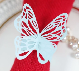 Detail of light blue laser-cut butterfly paper napkin ring on a red cloth napkin