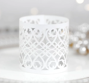 Macro detail of white laser-cut hollow candle shade with intricate vine patterns