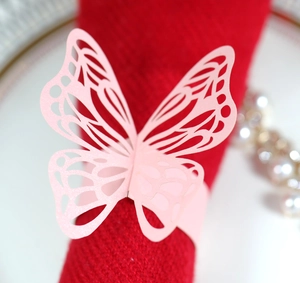 Pink laser-cut butterfly paper napkin ring shown on a red fabric for wedding table decor