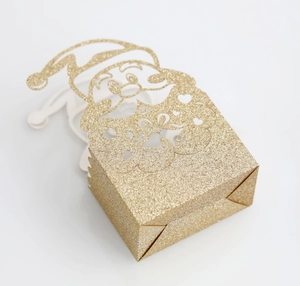 Close-up of golden glitter gift box featuring a hollow-out Santa Claus festive design