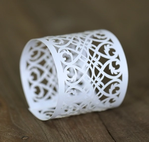 Close-up of white laser-cut hollow paper candle sleeve with elegant floral pattern