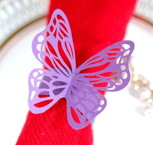 Close-up of purple laser cut butterfly napkin ring with pearlescent finish on red fabric
