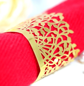 Golden hollow leaf napkin ring with metal plating on a red fabric napkin for table decor