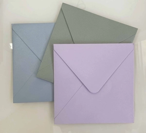 Dettaglio di tre buste in carta perlata di alta qualità in blu, verde e lilla