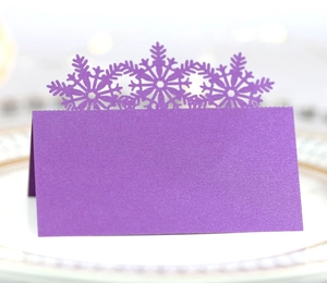 Detail of purple laser-cut snowflake place cards with pearlescent finish for wedding decor