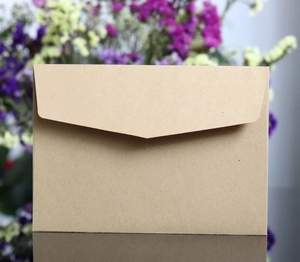 Classic kraft paper envelope with V-flap on reflective surface and floral background