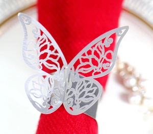 Detailed close-up of a silver butterfly napkin ring with hollow patterns on a red cloth