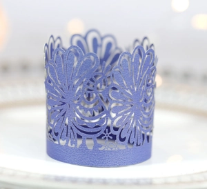 Close-up of laser-cut purple pearlescent paper cupcake wrappers with feather patterns