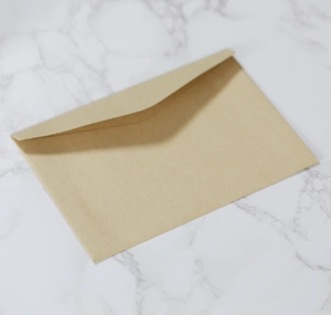 Top-down 45-degree angle view of a blank kraft paper envelope on white marble background