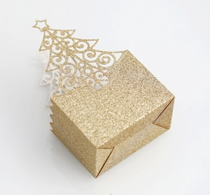 Macro detail of glitter gold Christmas tree gift box with laser-cut hollow patterns