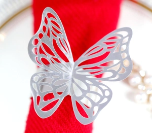 Close-up of silver cutout butterfly napkin ring with laser-cut wing details on red fabric